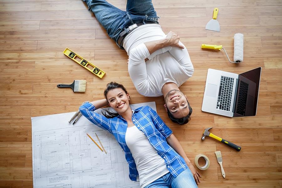 Retrato de una feliz pareja latinoamericana trabajando en un proyecto de vivienda rodeada de herramientas y mirando a la cámara.
