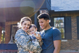 Young military family in front of new home
