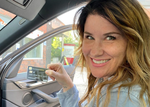 mujer en coche sosteniendo una tarjeta de crédito